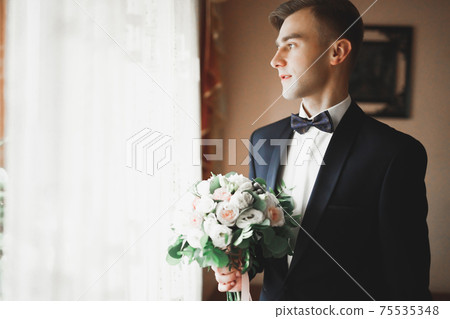 Grooms morning preparation. Handsome man getting dressed and preparing for the wedding 75535348