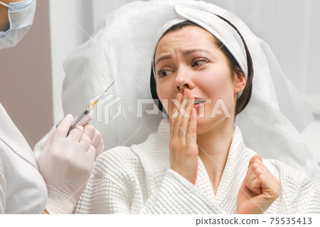 The doctor cosmetologist makes the rejuvenating facial injections procedure for tightening and smoothing wrinkles on the face skin of a beautiful, young woman in a beauty salon. Cosmetology, skincare The doctor cosmetologist makes the rejuvenating facial injections procedure for tightening and smoothing wrinkles on the face skin of a beautiful, young woman in a beauty salon. Cosmetology, skincare 75535413