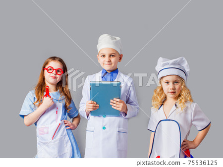 Cute little children dressed as doctors on grey 75536125