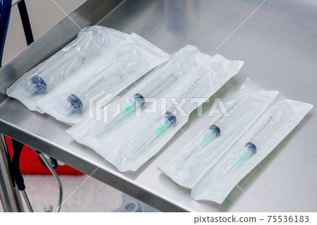 Syringes in packaging on a metal table in the operating room. Syringes in packaging on a metal table in the operating room. 75536183