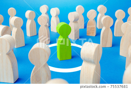 Figurine of green man stands in a white circle among a large crowd of people. Personal space, comfort zone. Protection and privacy concept. Immunity security. Keep distance. Isolate from society 75537681