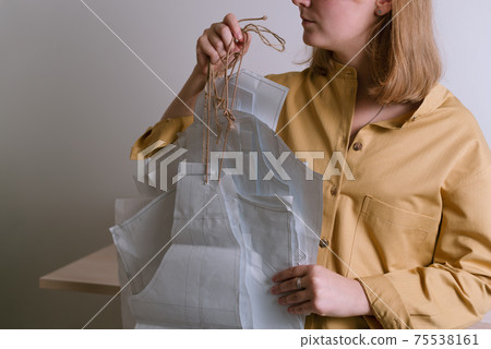 Female in yellow shirt holding paper dress patterns in her workshop Female in yellow shirt holding paper dress patterns in her workshop 75538161