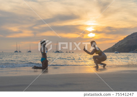 two ladies taking pictures on the beach. two ladies taking pictures on the beach. 75541247
