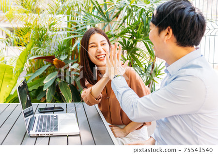 Happy couple giving high-five in cafe 75541540