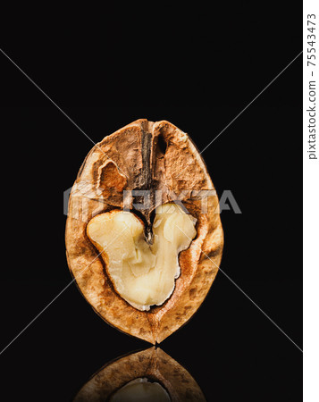 Walnut on black background. Low key style. Nut cut 75543473