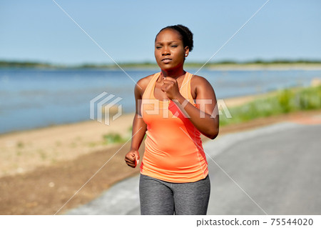 young african american woman running at seaside 75544020