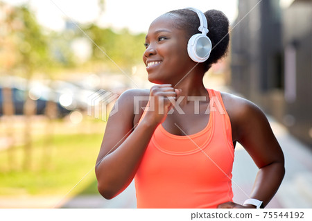 happy african woman in headphones running outdoors happy african woman in headphones running outdoors 75544192