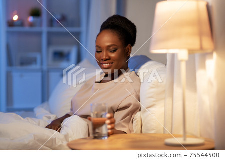 african woman drinking water in bed at night african woman drinking water in bed at night 75544500