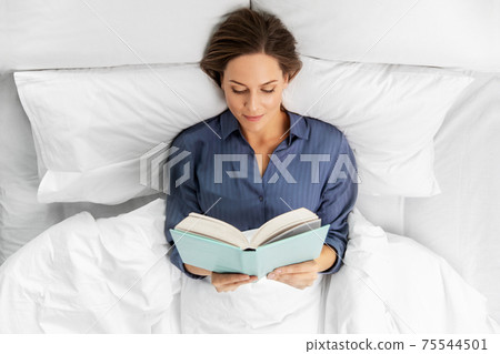 young woman reading book in bed at home young woman reading book in bed at home 75544501