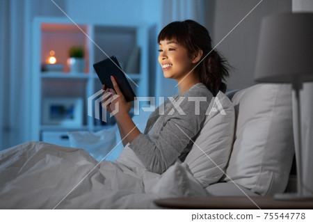 asian woman with tablet pc in bed at home at night asian woman with tablet pc in bed at home at night 75544778