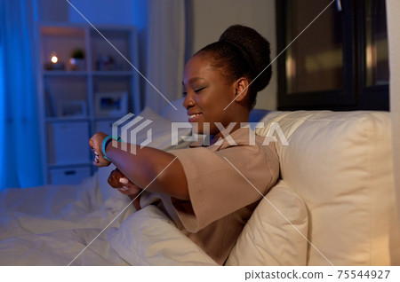 woman with health tracker in bed at night woman with health tracker in bed at night 75544927