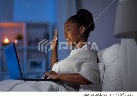 woman with laptop has video call in bed at night 75545133