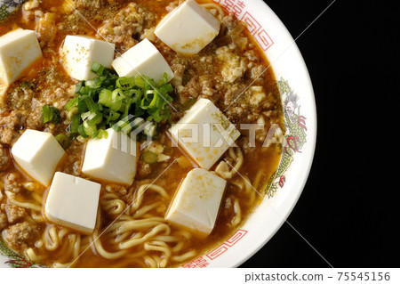 麻婆豆腐拉麵和日本胡椒，在黑色背景上拍了很多通用洋蔥（頂視圖） 75545156
