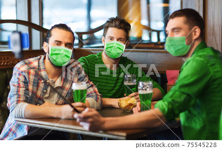 friends take selfie and drinking green beer at bar 75545228