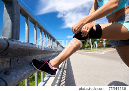 young woman in knee band doing sports outdoors young woman in knee band doing sports outdoors 75545286