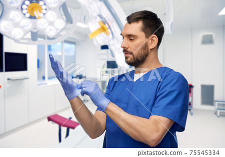 doctor or male nurse putting medical gloves on 75545334