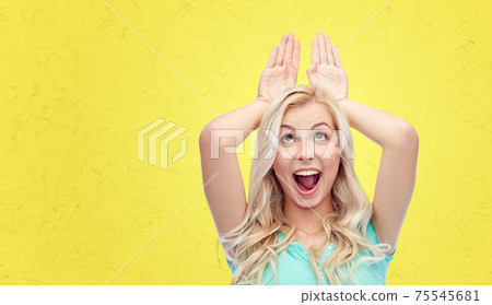 happy smiling young woman making bunny ears happy smiling young woman making bunny ears 75545681