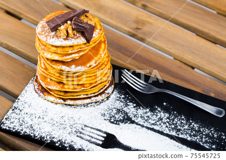 Stack of sweet pancakes with chocolate, walnut and powdered sugar Stack of sweet pancakes with chocolate, walnut and powdered sugar 75545725