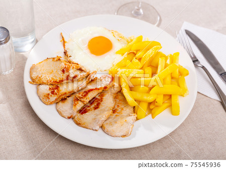 traditional spanish fried pork with fries served on blue plate on wooden table traditional spanish fried pork with fries served on blue plate on wooden table 75545936