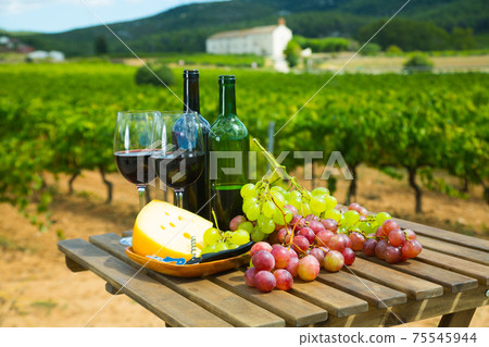 Red wine, cheese and grapes on wooden table 75545944