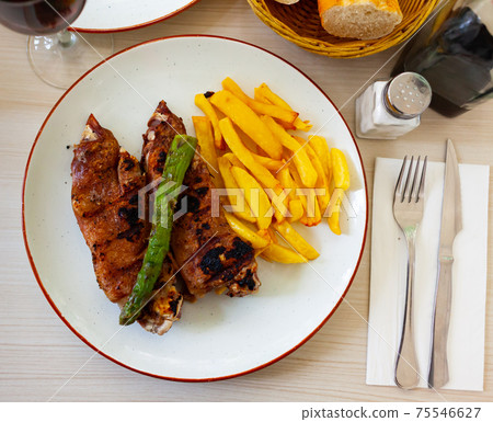 close up of grilled pigs trotter with fried potato and asparagus served on white plate on wooden table close up of grilled pigs trotter with fried potato and asparagus served on white plate on wooden table 75546627