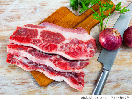 Sliced slices of raw beef meat on chopping plate with spices next to it Sliced slices of raw beef meat on chopping plate with spices next to it 75546679