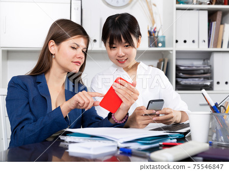 Two businesswomen working with smartphone in the office Two businesswomen working with smartphone in the office 75546847