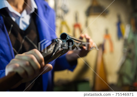 Break-action of horizontal double-barreled shotgun in hands of gunsmith 75546971