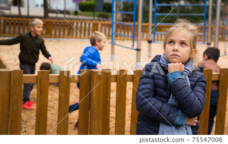 Upset girl on the background of playing children Upset girl on the background of playing children 75547006