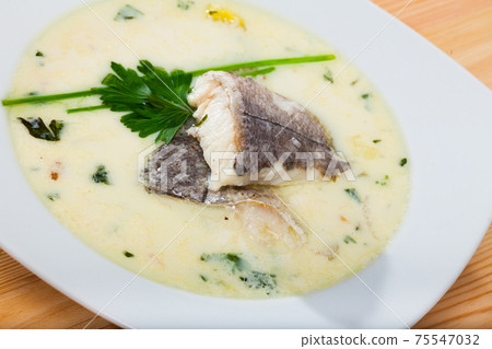 Creamy soup with white fish hake served with greens at plate Creamy soup with white fish hake served with greens at plate 75547032