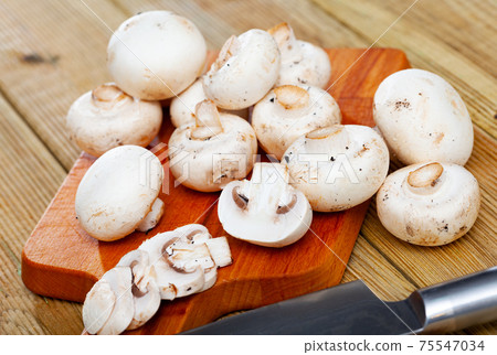 Fresh champignon mushrooms on a wooden cutting board Fresh champignon mushrooms on a wooden cutting board 75547034