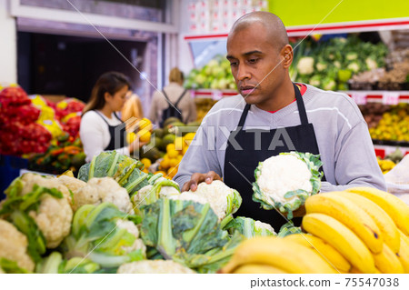 Portrait of latino-american worker in supermarket with vegetable Portrait of latino-american worker in supermarket with vegetable 75547038
