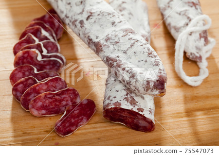 Spanish sausage fuet on a wooden table, closeup Spanish sausage fuet on a wooden table, closeup 75547073
