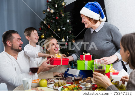 Senior woman presenting Christmas gifts to family Senior woman presenting Christmas gifts to family 75547152