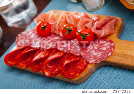 Spanish tasty meal slicing sausages and jamon with tomatoes, close up Spanish tasty meal slicing sausages and jamon with tomatoes, close up 75547231
