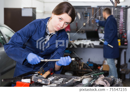 Woman is choosing instruments for repair car in workplace 75547235