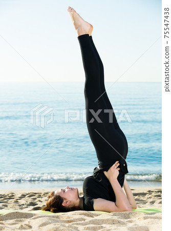 Adult woman in black T-shirt is stretching Adult woman in black T-shirt is stretching 75547438