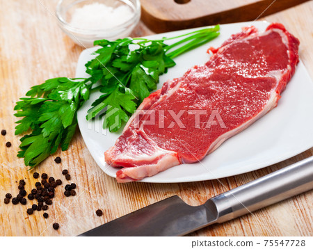 Piece of raw boneless beef with seasonings and greens Piece of raw boneless beef with seasonings and greens 75547728