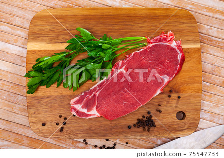 Sliced pieces of raw beef tenderloin on wooden cutting board Sliced pieces of raw beef tenderloin on wooden cutting board 75547733