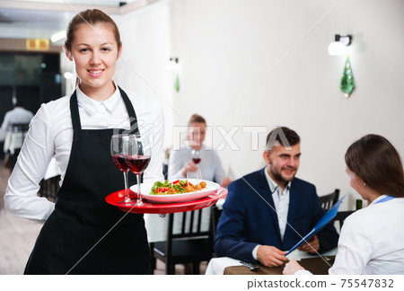 Portrait of woman waiter who is standing with dish in restaurante Portrait of woman waiter who is standing with dish in restaurante 75547832
