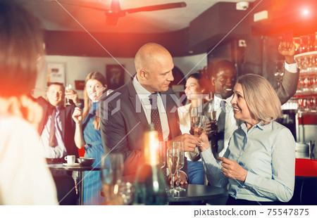 Cheerful middle aged woman with male colleague enjoying office p 75547875