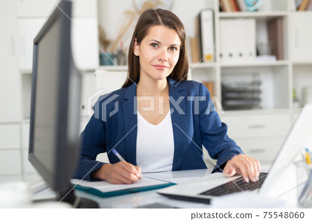 Successful female entrepreneur at office desk with papers and laptop Successful female entrepreneur at office desk with papers and laptop 75548060