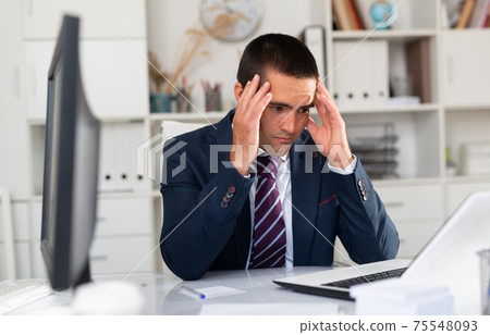 Tired businessman working with documents in office 75548093