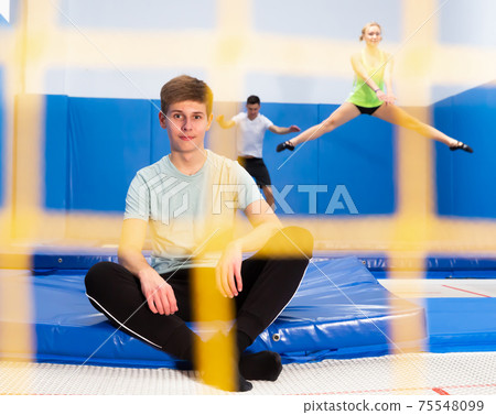 Male teenager resting during trampoline workout 75548099