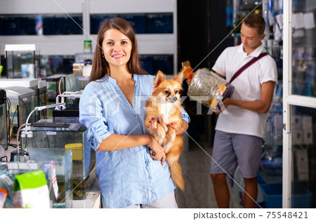 Woman with dog with interest looking at small aquarium 75548421