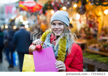 Happy girl chooses Christmas toys on the street market Happy girl chooses Christmas toys on the street market 75548423