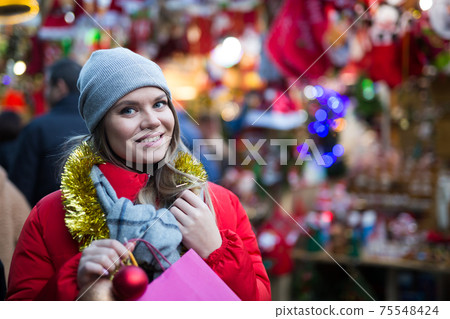 Girl choosing Christmas gifts outdoor on street market Girl choosing Christmas gifts outdoor on street market 75548424