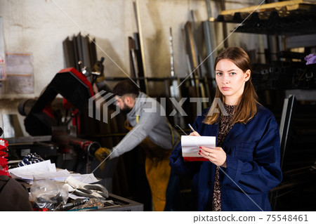 Young female standing with notepad in production workshop 75548461