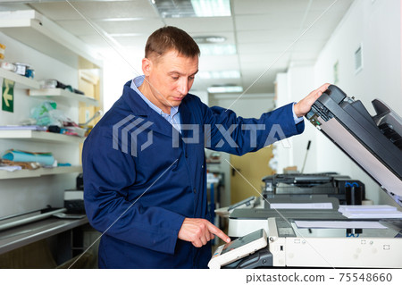 Portrait of confident service engineer standing by photocopy machine in office 75548660