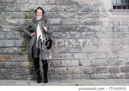girl in hood standing near stone wall girl in hood standing near stone wall 75548810